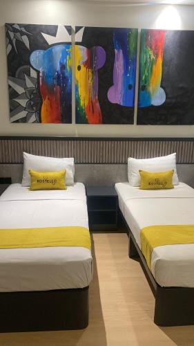 two beds in a room with paintings on the wall at Kostello Rajawali in Palembang