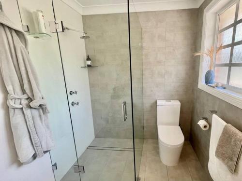 a bathroom with a toilet and a glass shower at The Cricket House - Family & Pet-Friendly Home in Bowral
