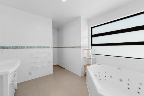 un bagno bianco con vasca e lavandino di Beachfront Paradise - Papamoa Beach Holiday Home a Papamoa