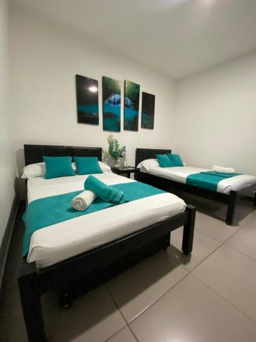 Dos camas en una habitación con azul y blanco. en Hotel Fermín, en Santa Rosa de Cabal