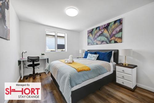 a white bedroom with a bed and a desk at Conservatorium Villa 2 in Orange