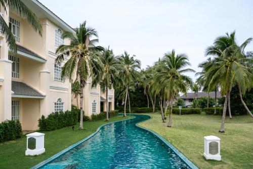 a swimming pool in front of a building with palm trees at Sofitel Krabi Phokeethra Golf and Spa Resort in Klong Muang Beach