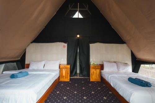 two beds in a tent with blue pillows at Popitan Garden Campground & Glamping Bedugul in Bedugul