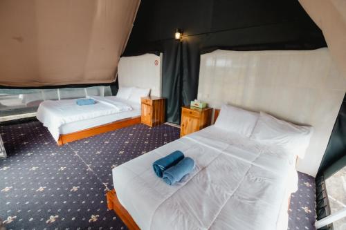 a bedroom with two beds with white sheets and a blue pillow at Popitan Garden Campground & Glamping Bedugul in Bedugul