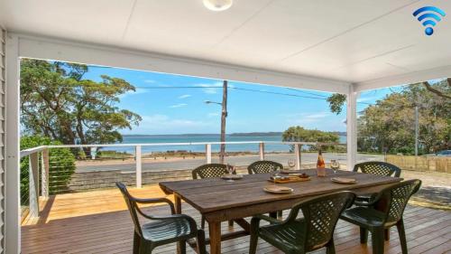 a dining table on a deck with a view of the ocean at Bellevue in Culburra Beach