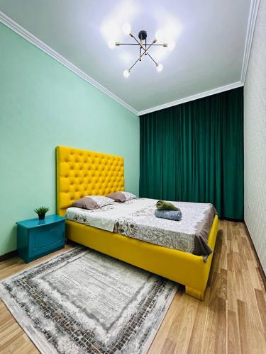 Un dormitorio con una cama amarilla y cortinas verdes. en ЖК Саулет Курылыс 5к1 70, en Aktobe