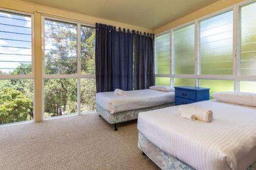 two beds in a room with large windows at Coastal Cove in Smiths Lake