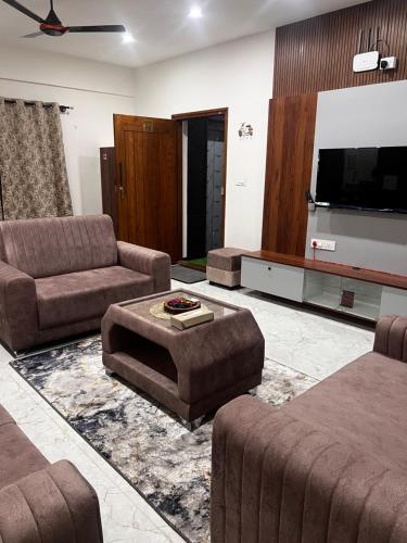 a living room with couches and a flat screen tv at SAHARHOMEstay O3 in Mysore