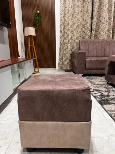 a large ottoman in a living room with a couch at SAHARHOMEstay O3 in Mysore