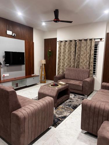 a living room with two couches and a flat screen tv at SAHARHOMEstay O3 in Mysore