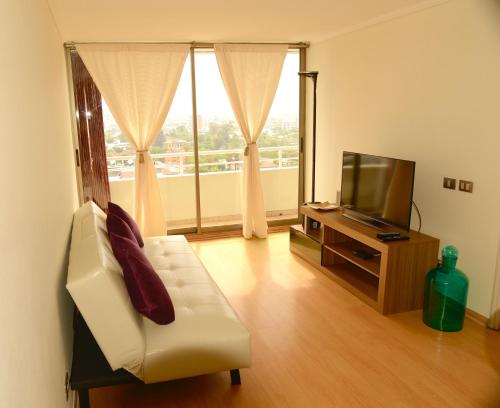 ein Wohnzimmer mit einem weißen Sofa und einem TV in der Unterkunft Chilean Suites Providencia II in Santiago