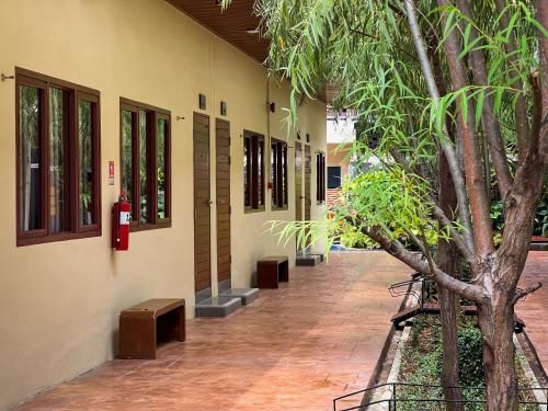 a building with benches and a fire hydrant next to a tree at Tachang Airport Hotel in Hat Yai