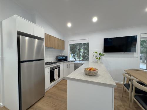 a kitchen with white cabinets and a table with a bowl of fruit at Tasman Holiday Parks - Kioloa Beach in Kioloa