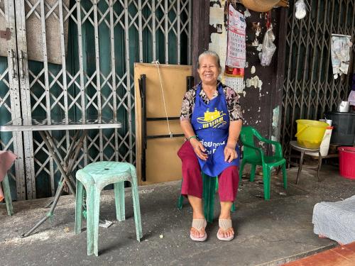 an older woman sitting on a chair in a room at Photohostel in Bangkok