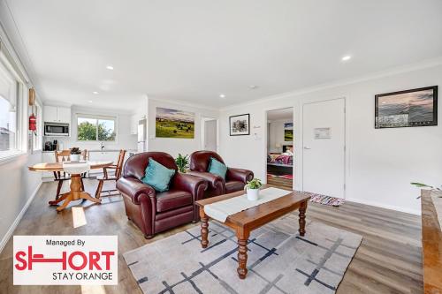 una sala de estar con un sofá y una mesa en Conservatorium Villa 3, en Orange