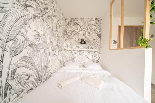 Una cama blanca en una habitación con papel pintado. en Les studios de l'Albatros, en Saint-Nazaire