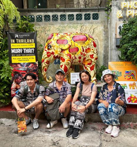 a group of people sitting in front of an elephant statue at Photohostel in Bangkok