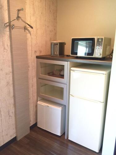 a microwave sitting on top of a counter next to a refrigerator at Bar 39 in Higashihiroshima