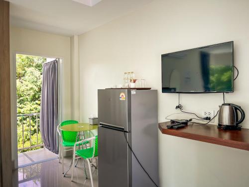 a kitchen with a refrigerator and a tv on the wall at Tachang Airport Hotel in Hat Yai