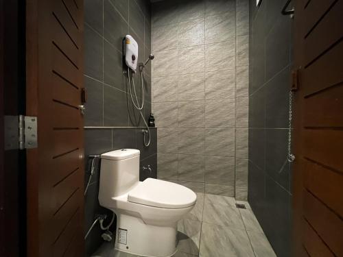 a bathroom with a toilet and a phone on the wall at Tachang Airport Hotel in Hat Yai