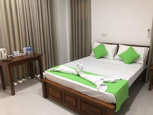 a bedroom with a bed with green and white sheets at Wildescape Polonnaruwa in Polonnaruwa