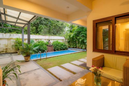 an open living room with a pool and a house at ELIVAAS 4 BHK with Pvt & Outdoor Sitting Area - Anasa in Goa