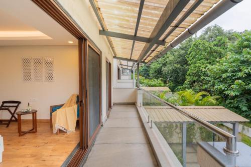 an open balcony with a view of the garden at ELIVAAS 4 BHK with Pvt & Outdoor Sitting Area - Anasa in Goa