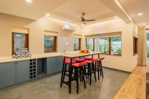 a kitchen with a island with red stools at ELIVAAS 4 BHK with Pvt & Outdoor Sitting Area - Anasa in Goa