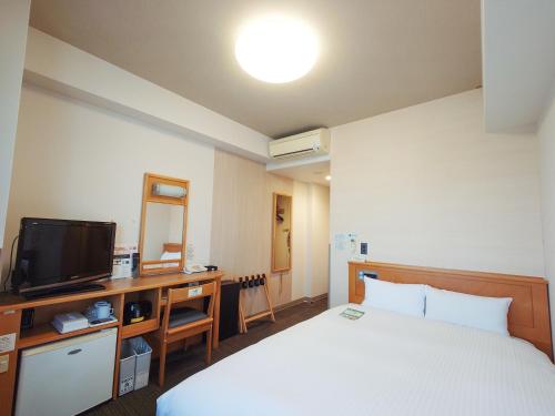 a hotel room with a bed and a television at Hotel Route-Inn Shibata Inter in Shibata