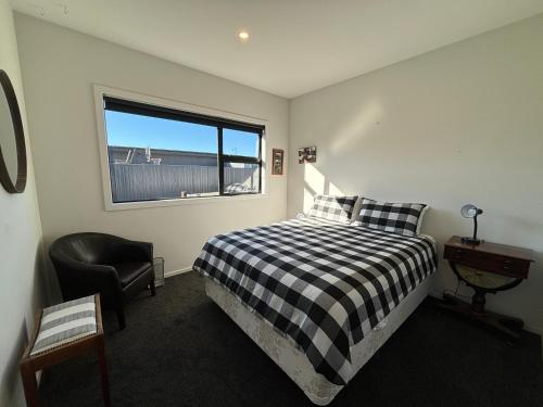 a bedroom with a bed and a chair and a window at Pedal and Play - Cromwell Holiday Home in Cromwell