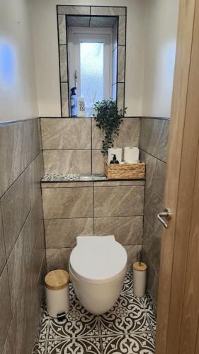 a bathroom with a toilet on a tiled floor at Beautifully Fab 3 bedroom 7 guests house in Farnworth