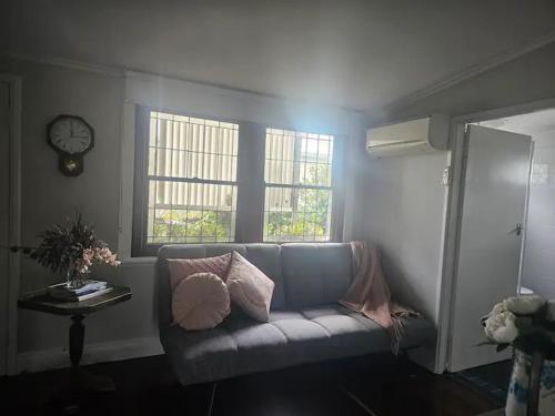 a living room with a couch and two windows at Ellson House - The Heart of the Hunter in Cessnock