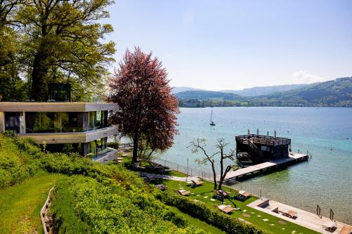 a house on the shore of a lake with a boat at Hotel Attersee in Seewalchen
