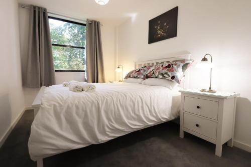 a bedroom with a large white bed with a window at Modern Comfort Near Castle St with WiFi & Parking! in Taunton