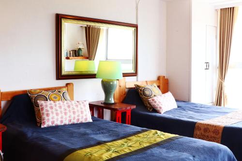 two beds in a room with a mirror and a lamp at Minamiboso Asian Garden Villa Shirahama in Minamiboso