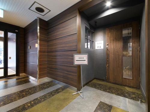 a hallway with wood paneling and a sign on a stand in a building at APA Hotel TKP Sapporo Ekimae in Sapporo