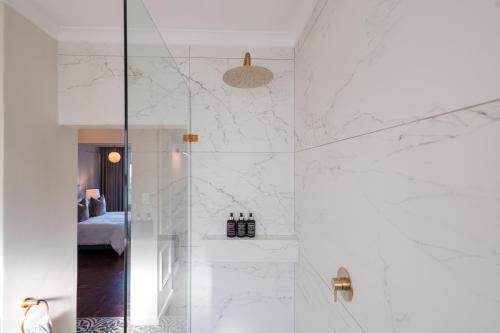 a bathroom with a shower with white marble walls at 201 Cascades l 2 Bed Boutique Aparthotel in Cape Town