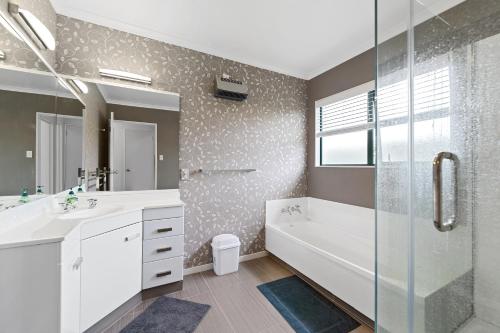 a bathroom with a tub and a sink and a shower at Fernwood Escape - Tauranga Holiday Home in Tauranga