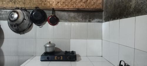 a kitchen with pots and pans hanging from a wall at Noor Homestay Tetebatu in Tetebatu