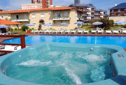 a large blue swimming pool with a hotel in the background at Hotel Tejas Rojas in Villa Gesell