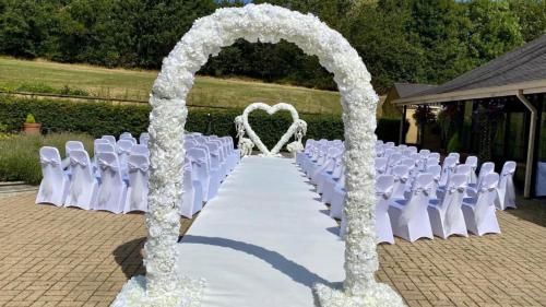 a wedding aisle with white chairs and an arch at Holiday Inn Leeds Brighouse by IHG in Brighouse