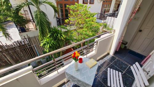 a table with a vase of flowers on a balcony at Minh Trang Villa Hoi An -BBQ Garden in Hoi An