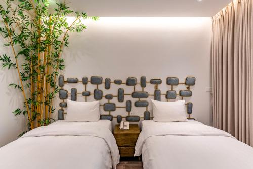 two beds in a room with white walls and plants at Mai Hotel in Hanoi