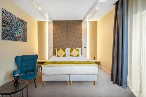 a bedroom with a bed and a blue chair at Hotel Ózon & Luxury Villas in Mátraháza