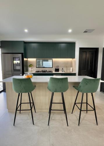 a kitchen with green cabinets and two bar stools at Modern & Chilled Stay in Bayswater in Perth