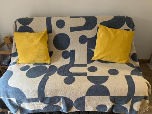 - un lit avec 2 oreillers jaunes et une couverture dans l'établissement Délicieux Studio 3 p climatisé La Faviere, à Bormes-les-Mimosas