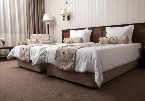 トリャブナにあるHotel Kalina Palaceのベッドルーム1室(白いシーツと枕のベッド2台付)