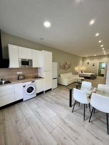 a kitchen and living room with white cabinets and a table and chairs at Califa SuitesGP in Córdoba
