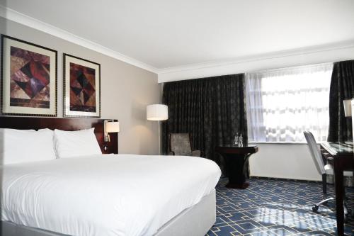 a hotel room with a bed and a desk and a window at Crowne Plaza Liverpool - John Lennon Airport by IHG in Liverpool