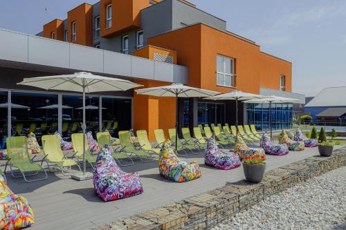 a row of colorful chairs and umbrellas in front of a building at Hotel TENIS in Zvolen